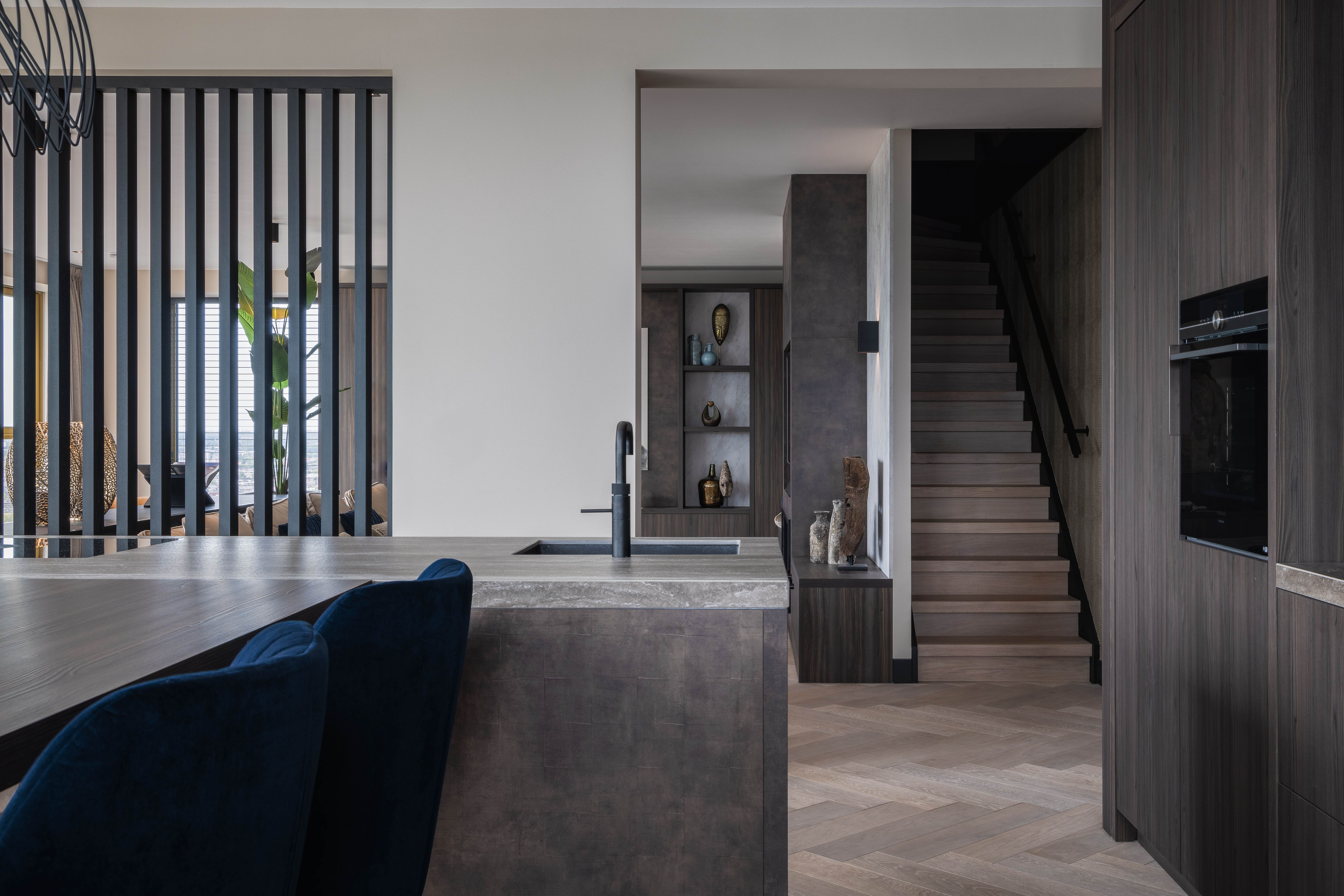 Penthouse - Keuken met stenen eiland en moderne trap naar boven